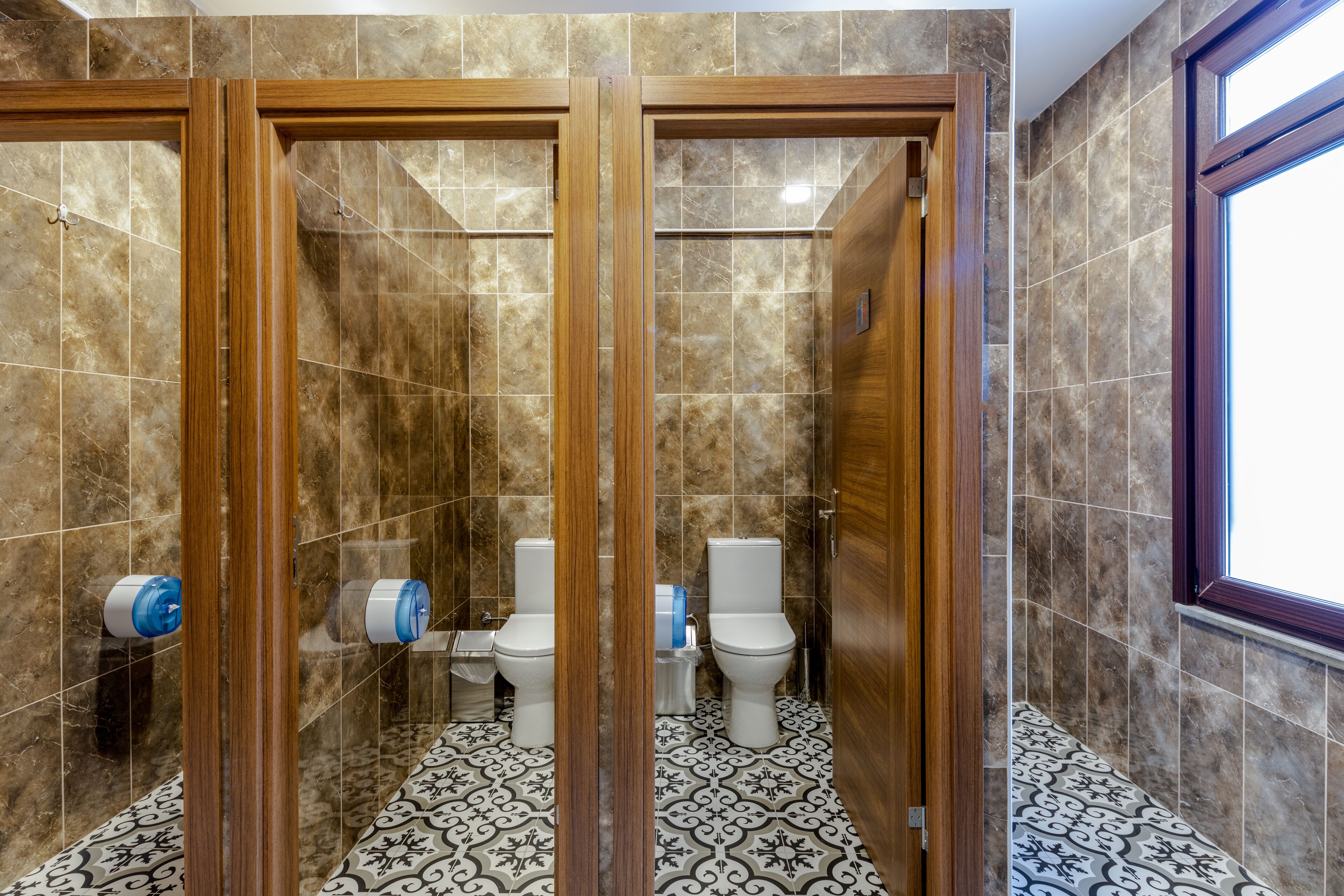 Une salle de bain avec deux toilettes, une douche et une fenêtre.