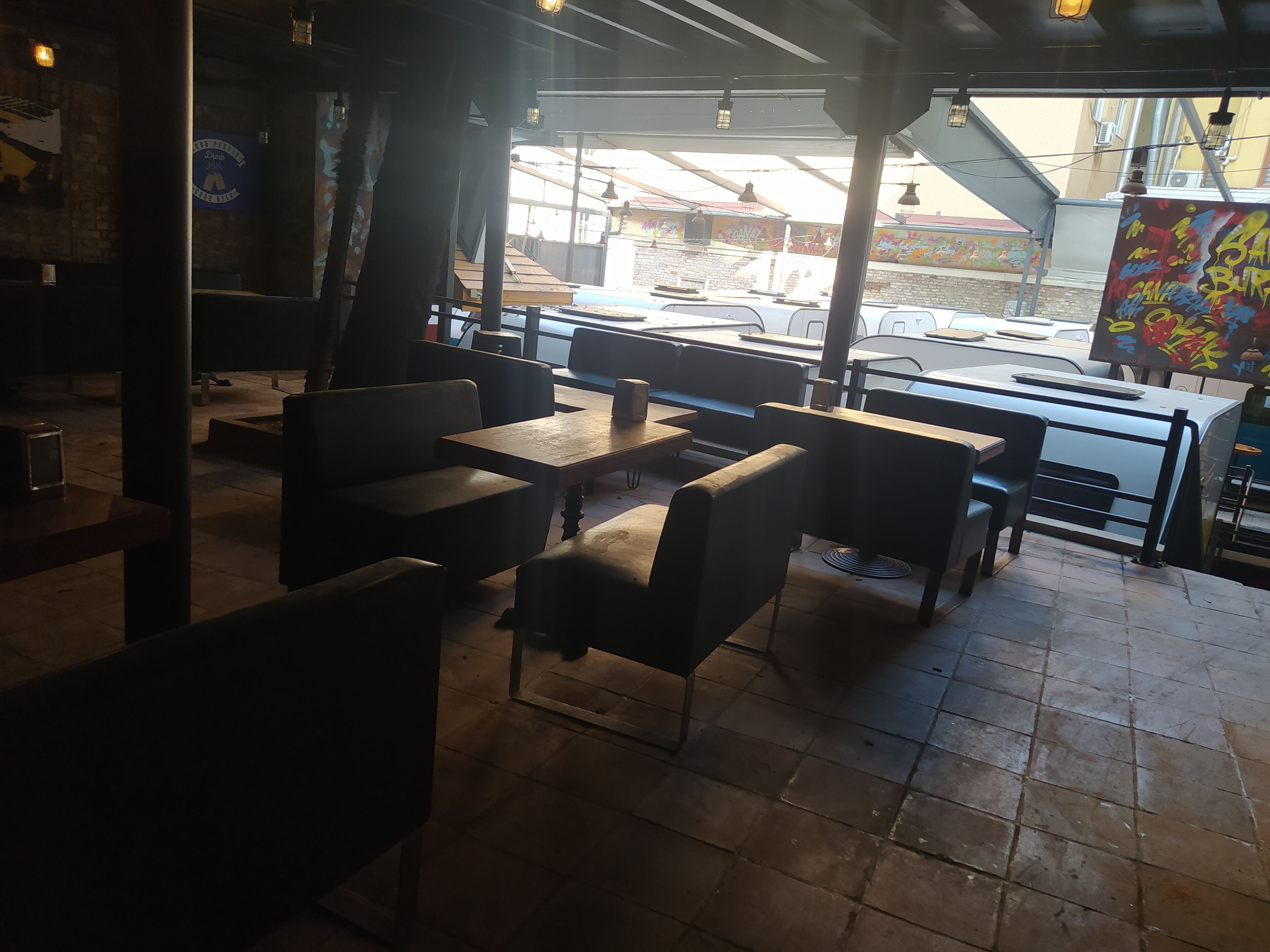 An indoor seating area with tables and chairs, large windows, and a view of the street outside.