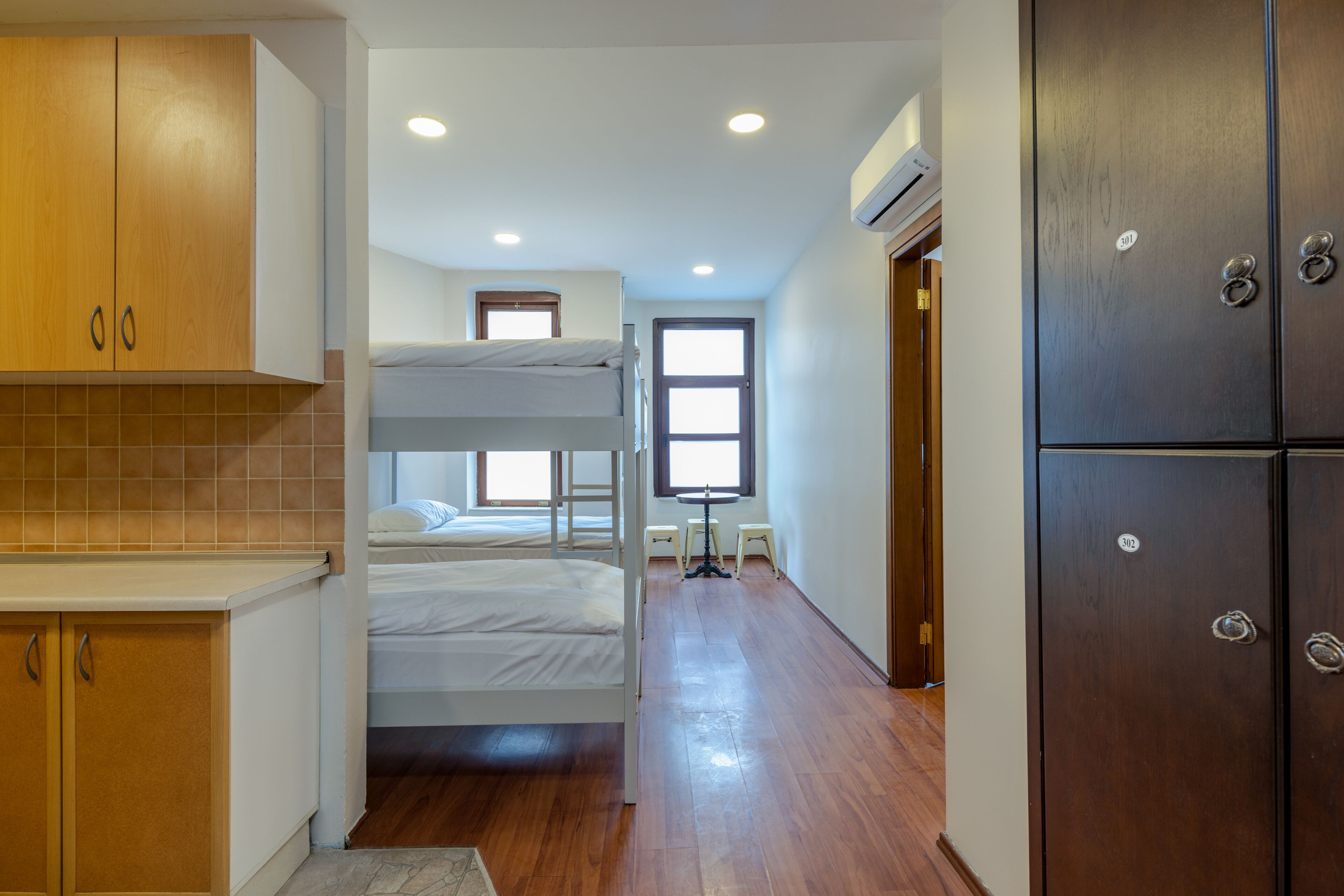 A compact hotel room with a bunk bed, wooden cabinets, a kitchenette, and a large wardrobe.
