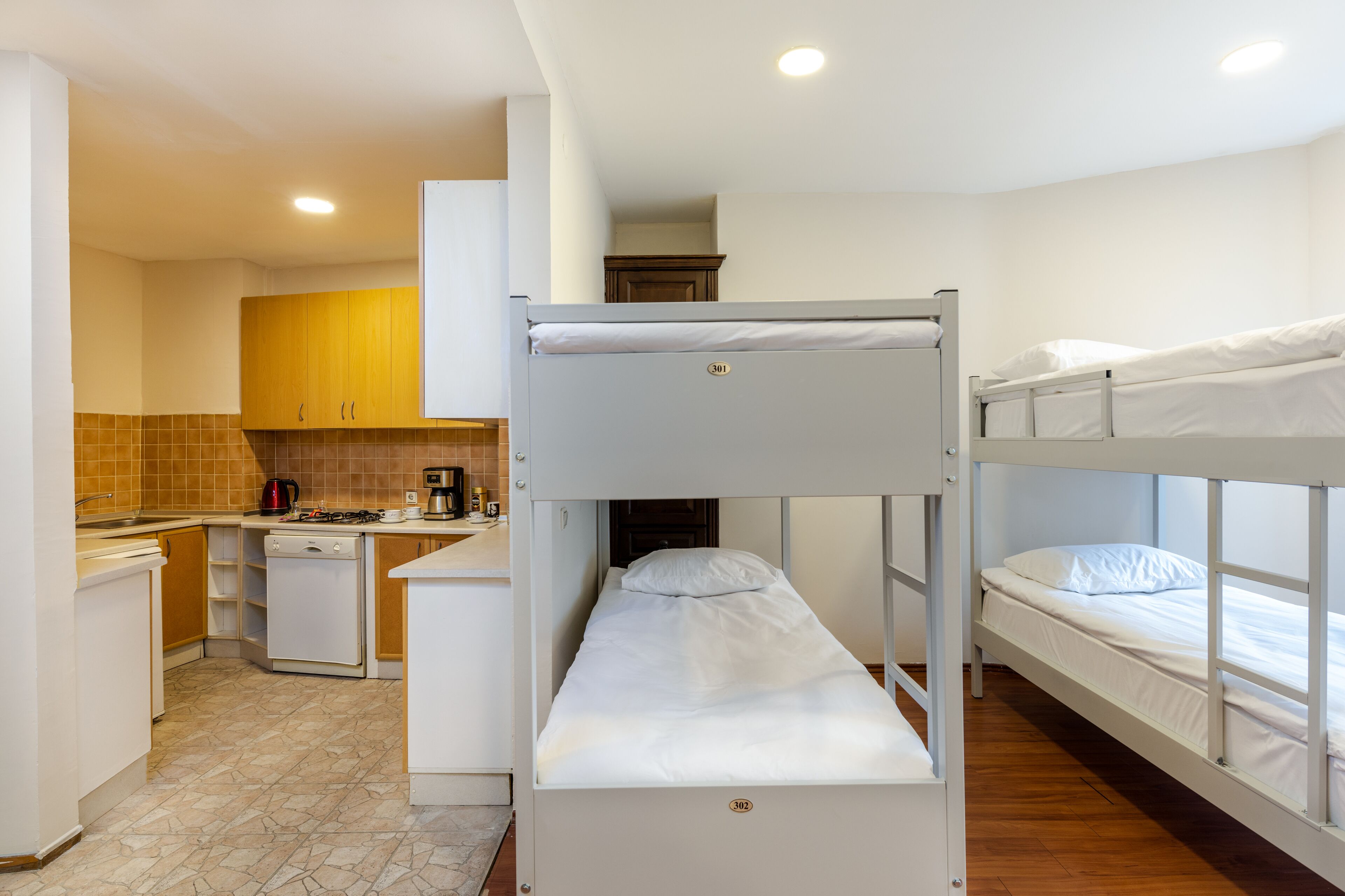 Una cama litera con un área de cocina que incluye un lavamanos, estufa y armarios.