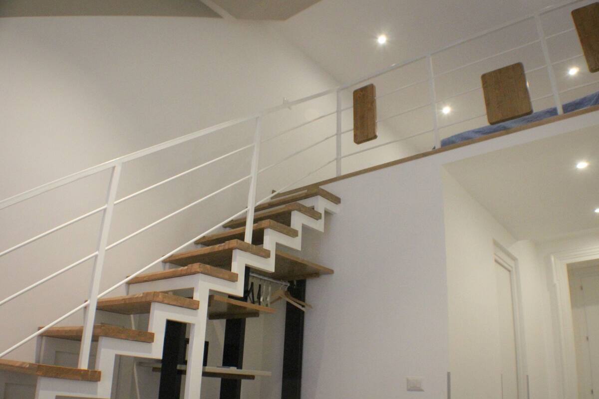 A modern staircase with wooden steps and white railings.
