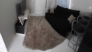 Pieni makuuhuone, jossa on sänky, televisio, pieni työpöytä ja tuoli.
