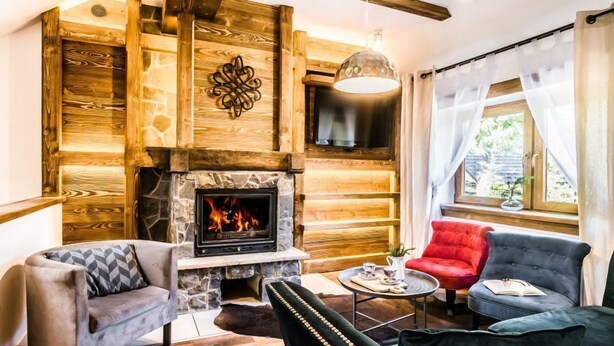 Een gezellige woonkamer met een stenen openhaard, houten wanden en moderne meubels.