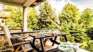 Een terras buiten met een houten eettafel, omringd door stenen muren en weelderige begroeiing.