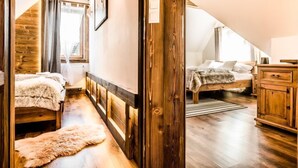 Een gezellig slaapkamer op zolder met een houten plafond, een groot raam en een rustieke houten garderobe.