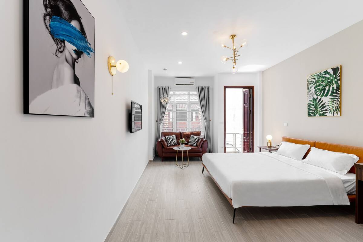 Una camera d'albergo moderna con un letto grande, un divano, un tavolino e una televisione.