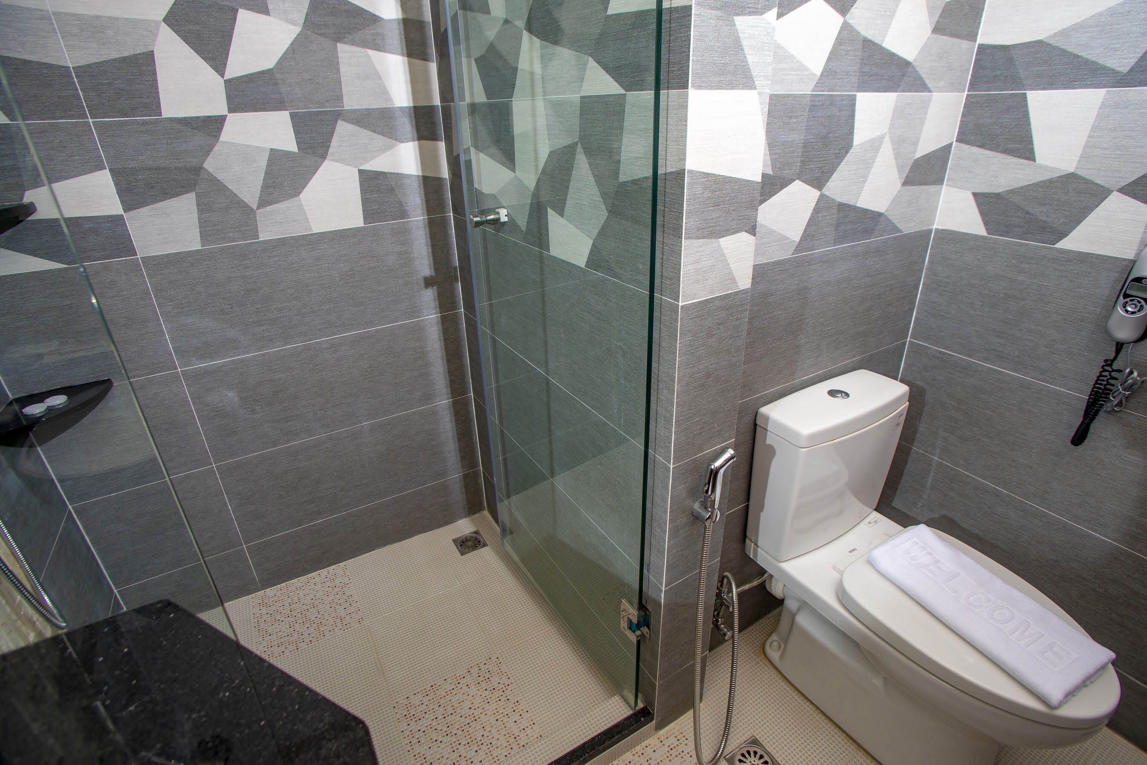 A bathroom with a shower, toilet, and a towel on the toilet.