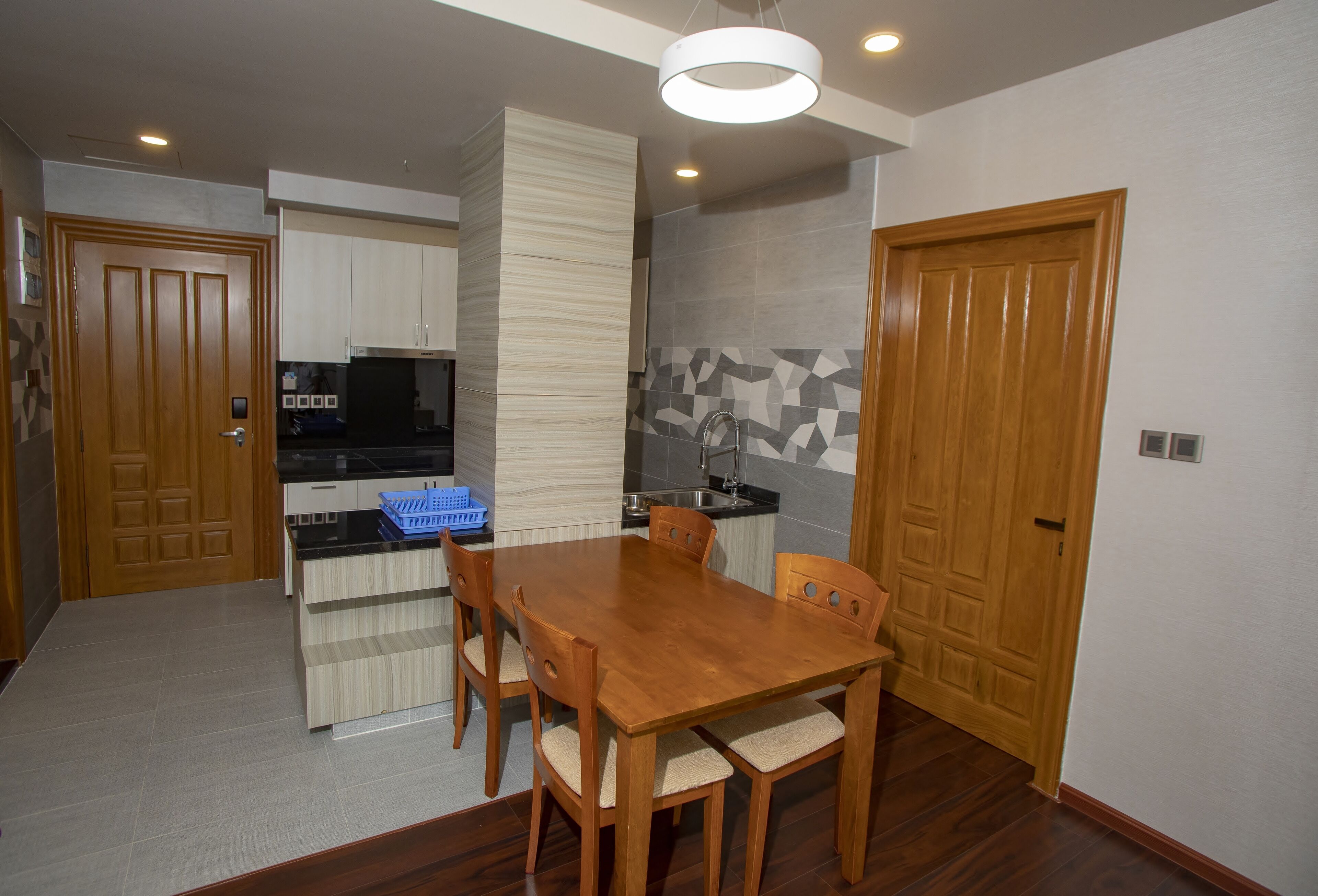 A compact kitchen with a dining area, wooden cabinets, a built-in stove, and a blue basket.