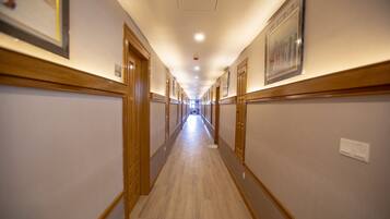 A long, narrow hallway with wooden paneling and framed pictures on the walls.