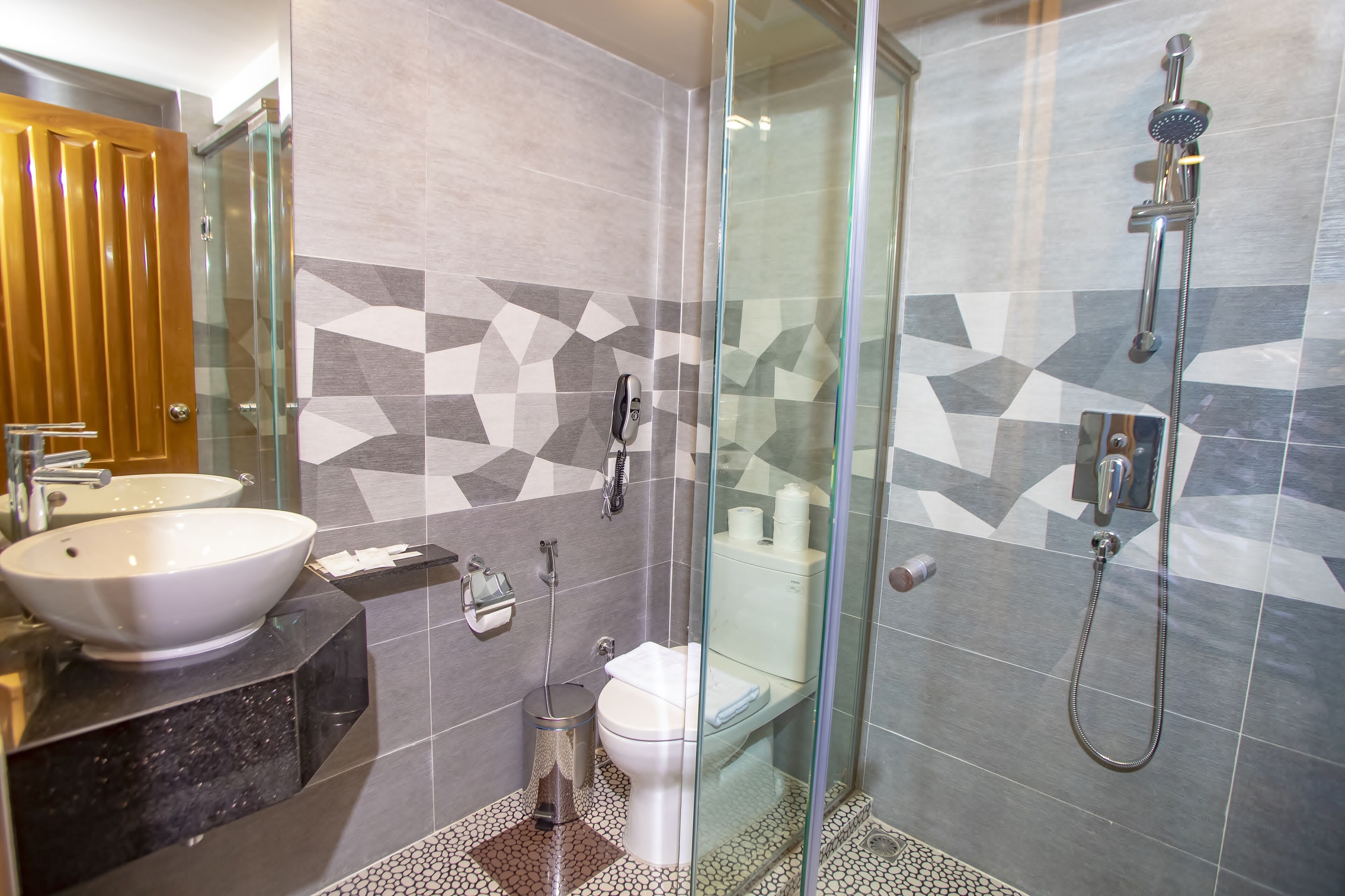 A modern bathroom with a glass-enclosed shower, a white sink, and a toilet.