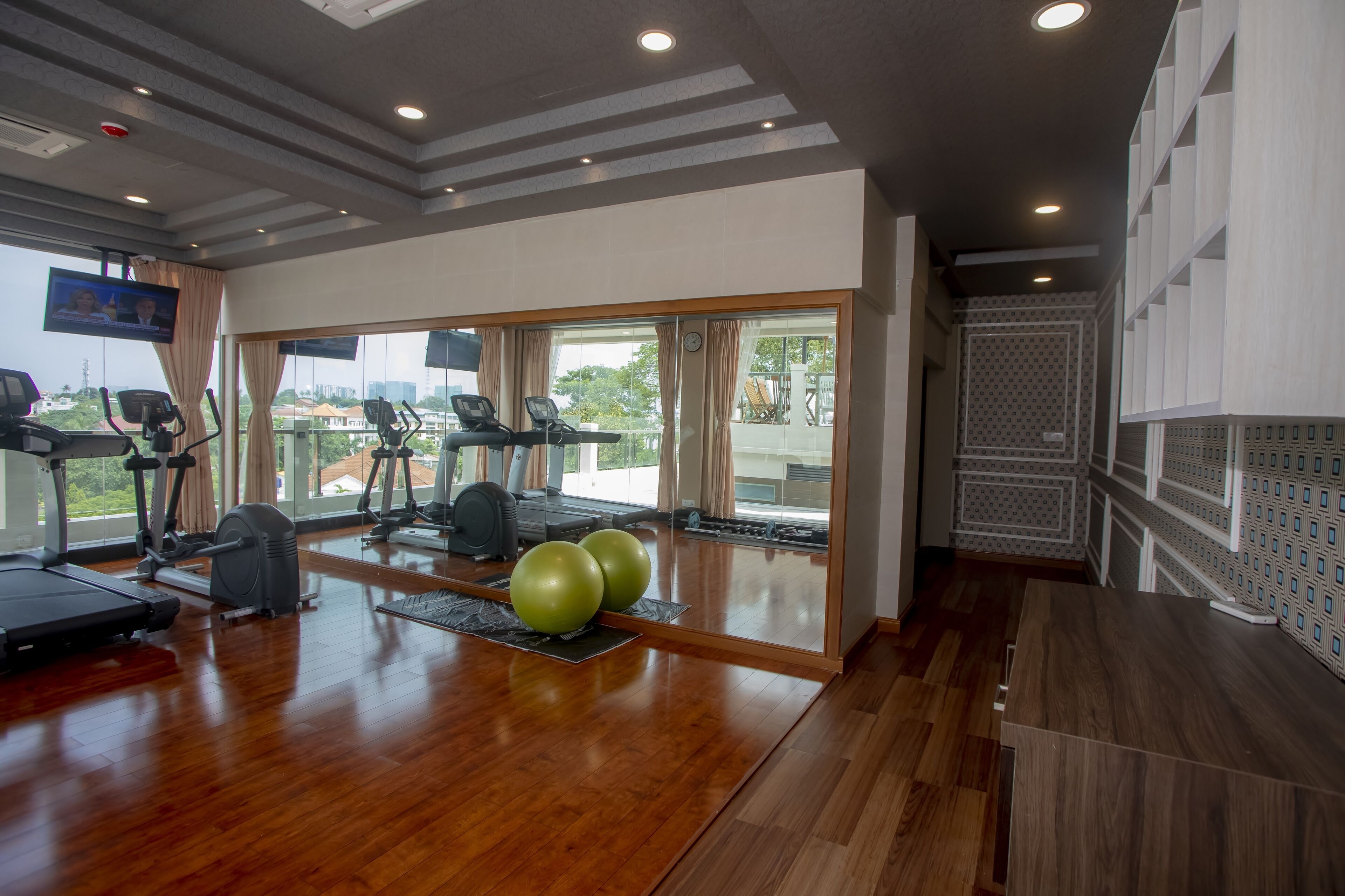 Un gimnasio con equipo de ejercicio, ventanas amplias y suelo de madera.