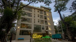 Et hotel med flere etager og et markant neonskilt med teksten "Prestige Residences Hotel & Serviced Apartments".