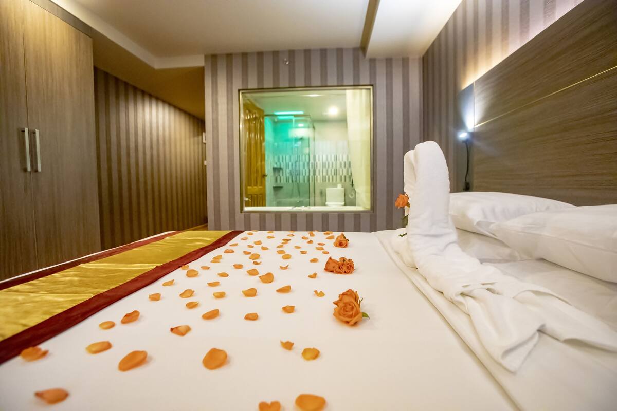 A hotel room with a bed, a mirror, and a window.