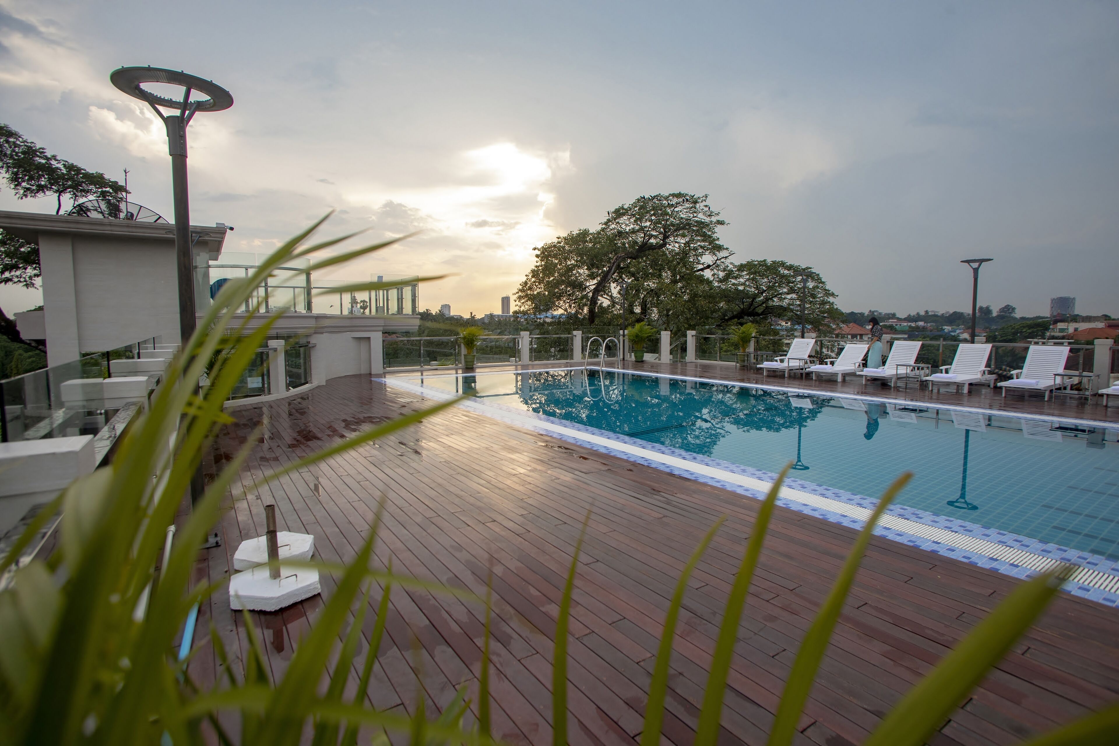 A rooftop pool area with lounge chairs and a view of the city skyline.