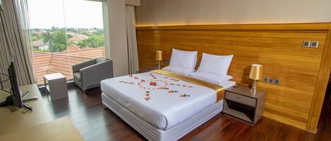 Quarto de hotel com uma cama grande, uma escrivaninha, uma cadeira e vista para a cidade.