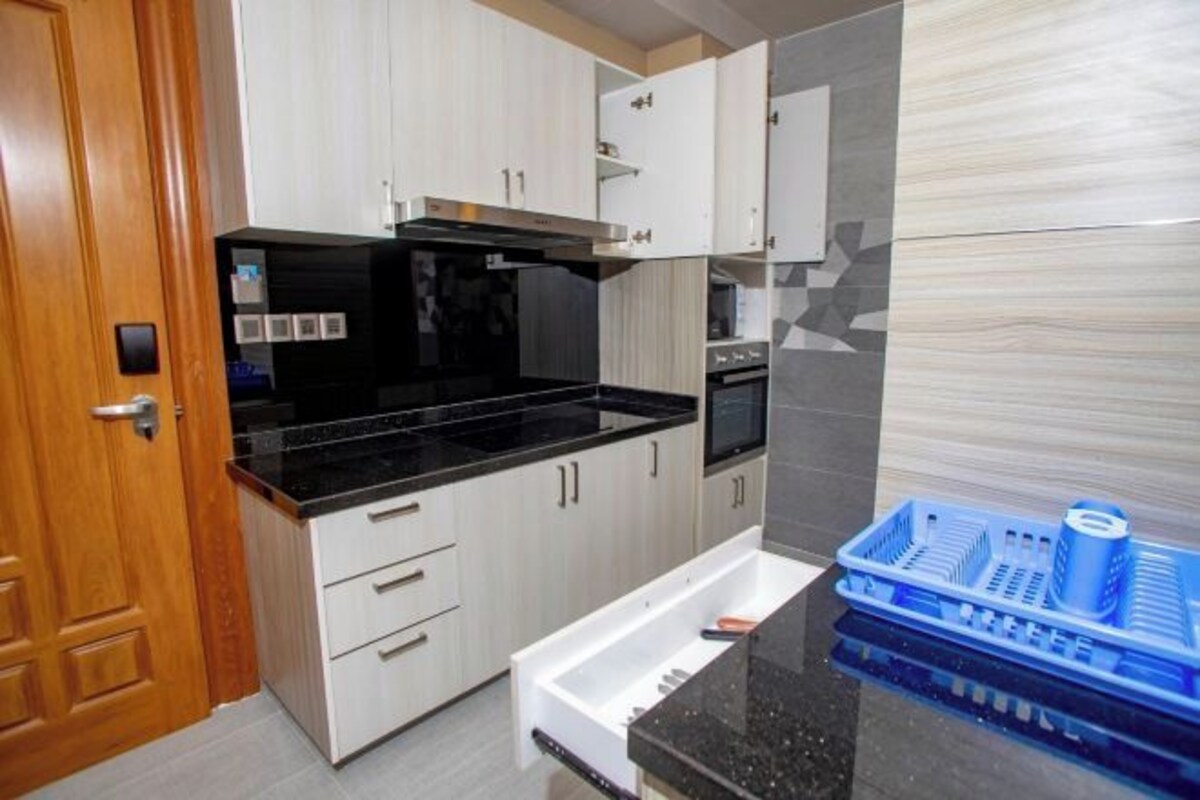 A kitchen with white cabinets, a black countertop, and a blue dish rack.