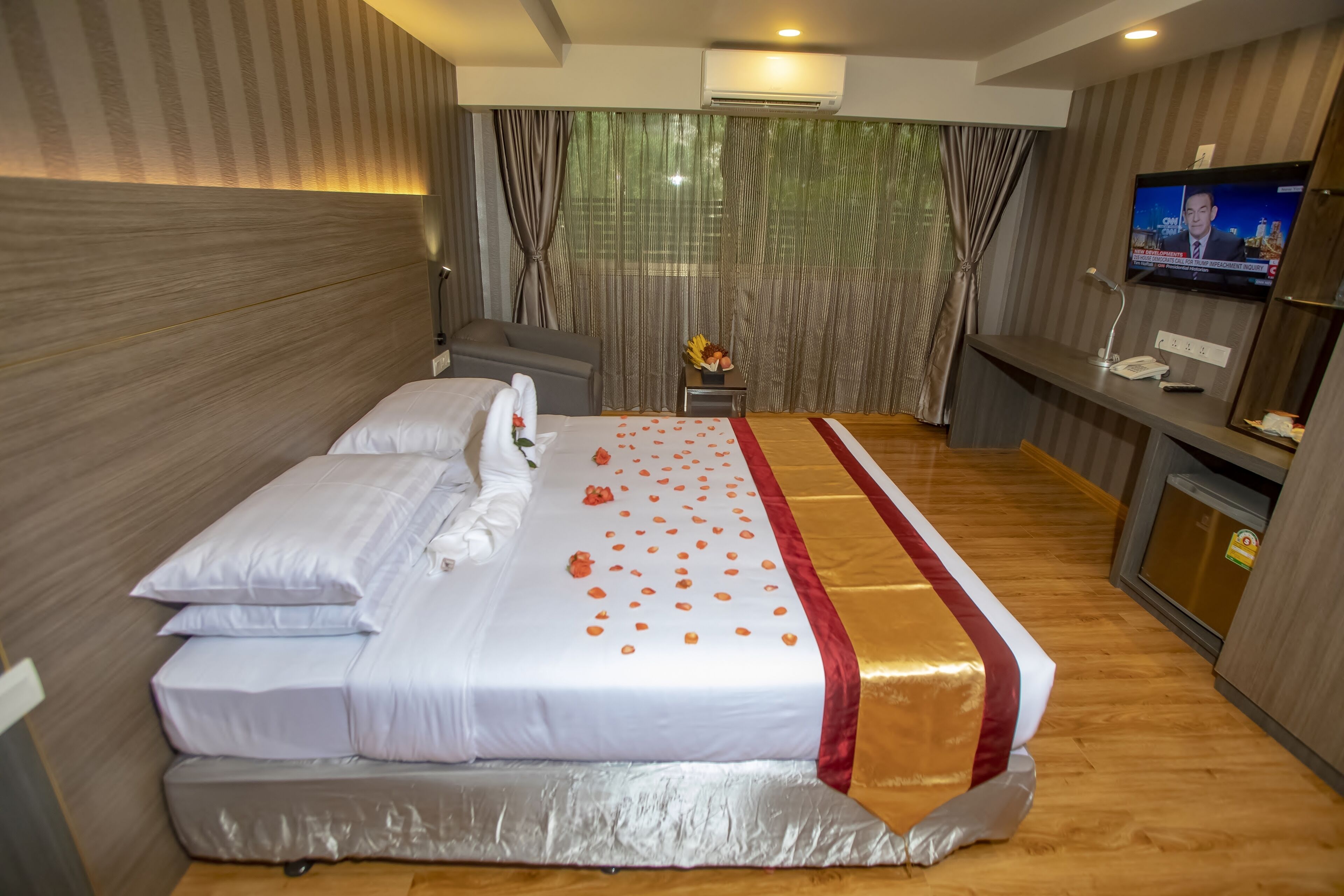 A hotel room with a large bed, a TV, a desk, and a chair.