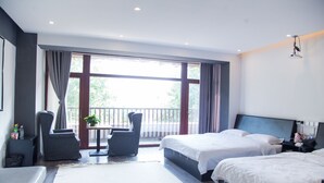 A hotel room with two beds, a balcony, a seating area with a table and chairs, and a large window providing a view of the outdoors. - Villa Haixin (Qingdao)