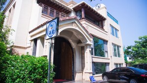 A two-story building with a traditional architectural style, featuring a prominent entrance with an archway, large windows, and a balcony with wooden railings. - Villa Haixin (Qingdao)