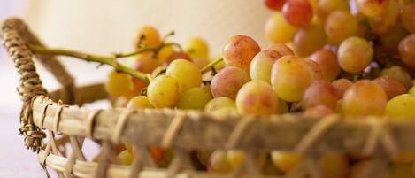 Una cesta de mimbre llena de uvas rojas y amarillas sobre una mesa.