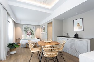 A modern, compact living space with a dining area, kitchenette, and a bed.