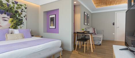 A modern bedroom with a large bed, a bench, a desk, and a chair.