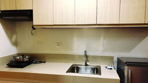 Une cuisine avec des meubles de couleur bois clair, un évier en acier inoxydable et une plaque de cuisson à induction noire.