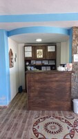 Un mostrador de recepción con paneles de madera, certificados en la pared y una alfombra estampada en el suelo.