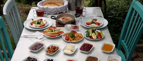 A table set outdoors with various dishes, including salads, bread, and a pot of rice.