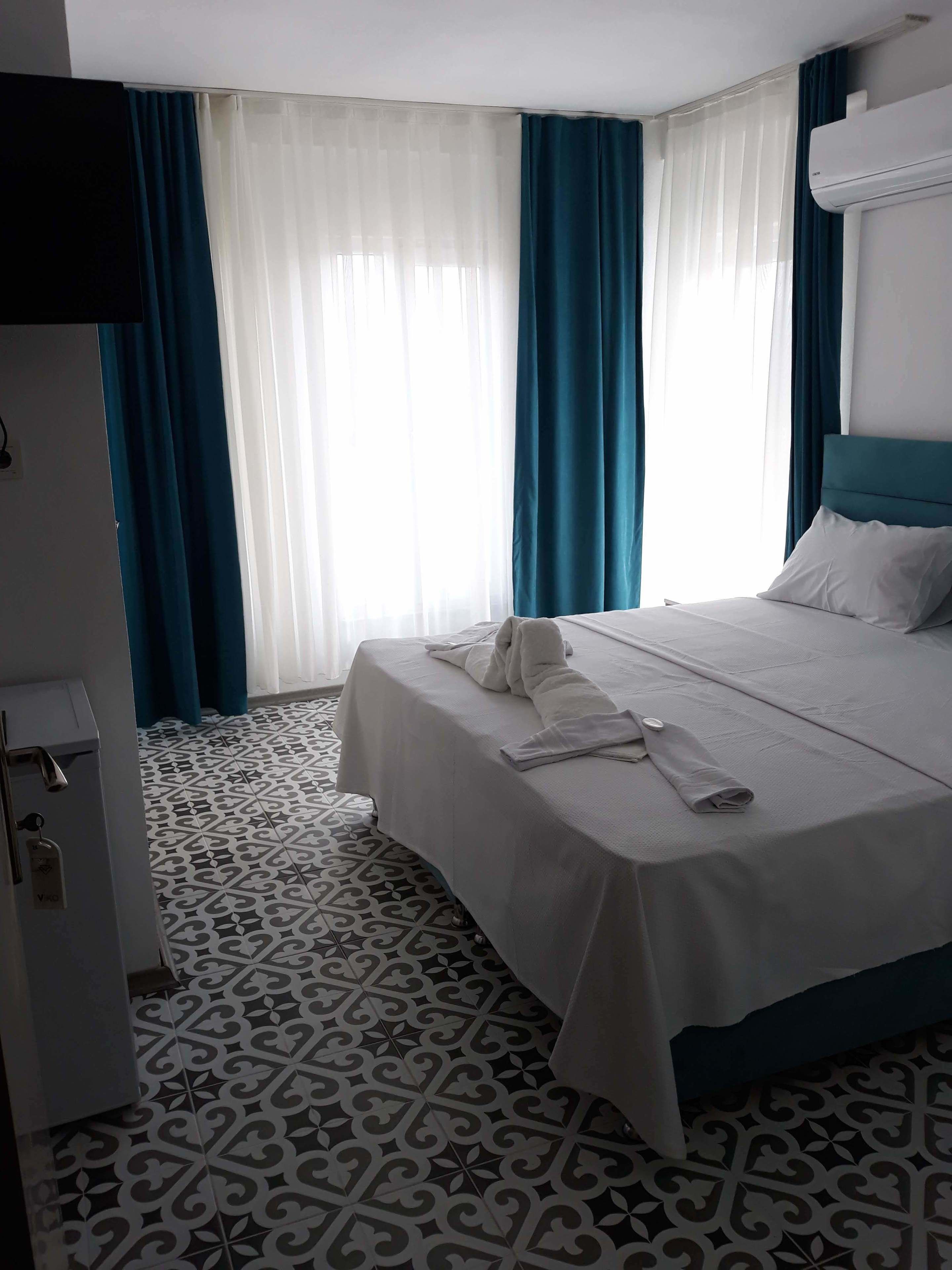 A hotel room with a bed, a wardrobe, and a patterned floor.