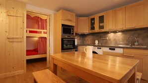 Une cuisine compacte avec des meubles en bois, un four à micro-ondes, un four traditionnel et un évier.