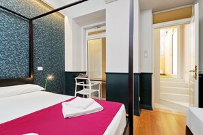 A hotel room with a bed, a desk, a chair, and a bathroom with a bathtub and toilet. - Cozy Vittoria Colonna (Rome)