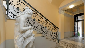 Un escalier en marbre orné d’une rampe décorative et surmonté d’une statue.