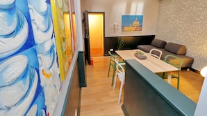 Un salon moderne avec un canapé, une table à manger et des chaises, ainsi qu’un tableau accroché au mur.
