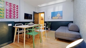 Un espace de vie compact comprenant un coin repas, un canapé et un téléviseur.