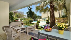 Una terrazza esterna con mobili in vimini, una piscina e diverse piante.