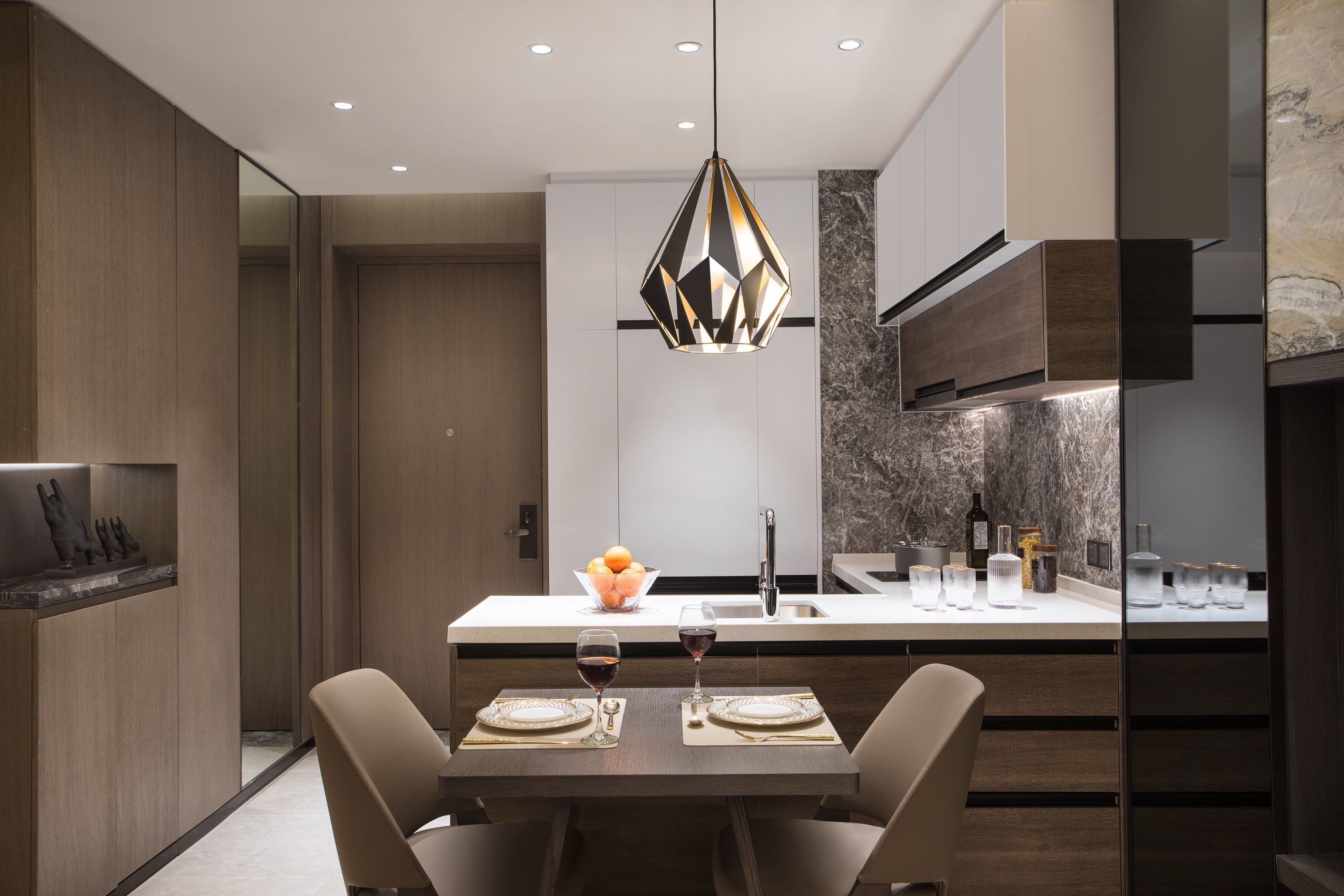 A modern kitchen with a central island, a dining area with two chairs, and a pendant light.