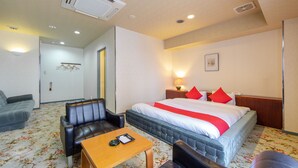 Ein Hotelzimmer mit Bett, einer Sitzecke, einem Tisch und Teppichboden.