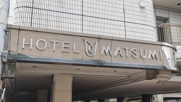 Ein Hotel Eingang mit einem Schild, auf dem 'HOTEL MATSUMI' steht.