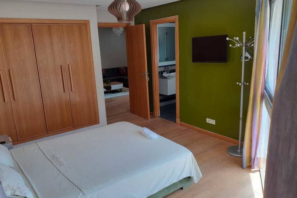 Un dormitorio con cama, armario y baño visible a través de una puerta abierta.