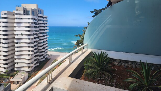 A modern building with a balcony overlooking a beach and ocean. - Marina Casablanca by Saloua (Casablanca)