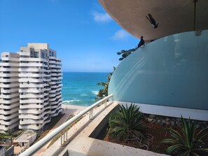 Un edificio moderno con balcón que da a una playa y al océano.