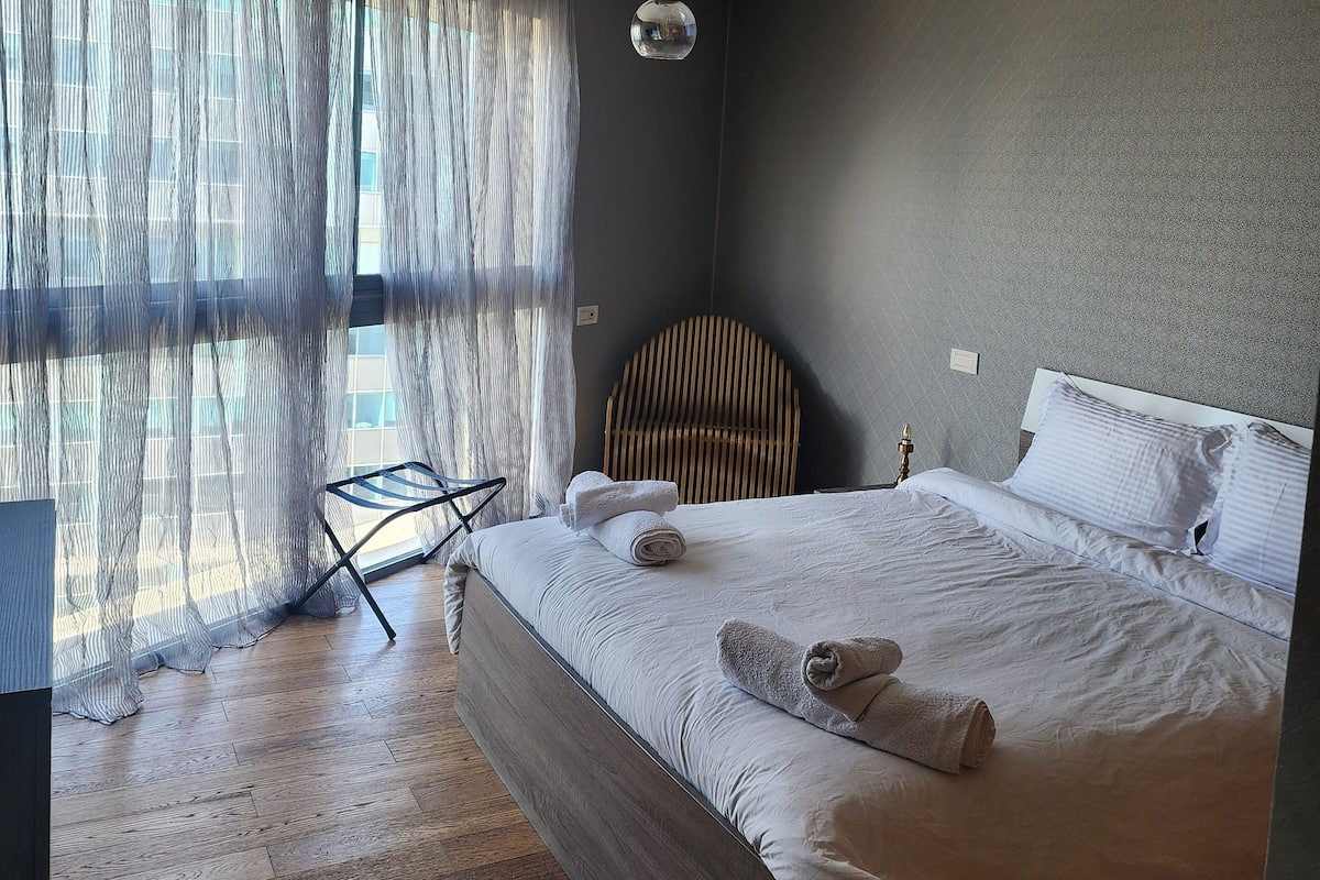 Un dormitorio con una cama grande, una silla y una lámpara colgante.