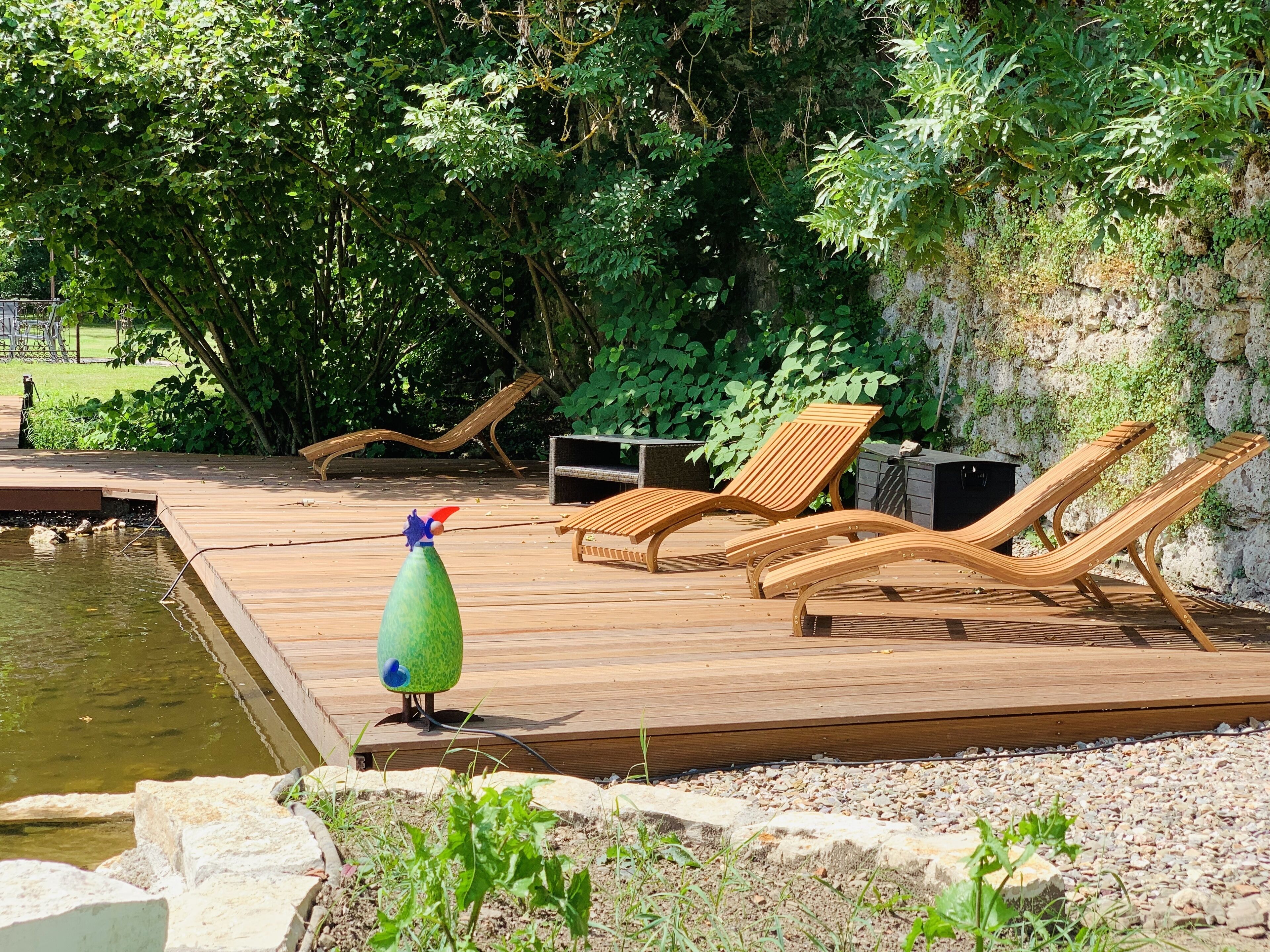 A wooden deck with lounge chairs and a small pond.