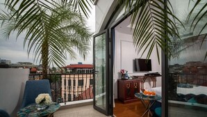 Un balcone con vista sulla città, una televisione su un mobile e un tavolino con arance.