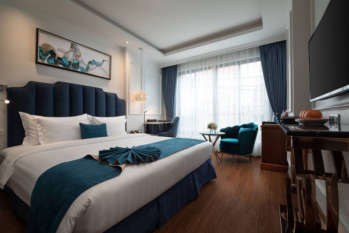 A modern hotel room with a large bed, a desk, and a TV.