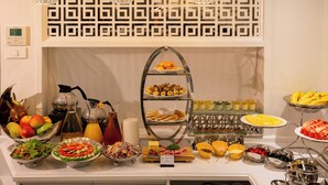 Un buffet con diverse pietanze e una parete decorativa con motivo geometrico.