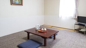 Una habitación con una mesa de madera, un cuadro en la pared, una ventana con cortinas y un televisor sobre un mueble.