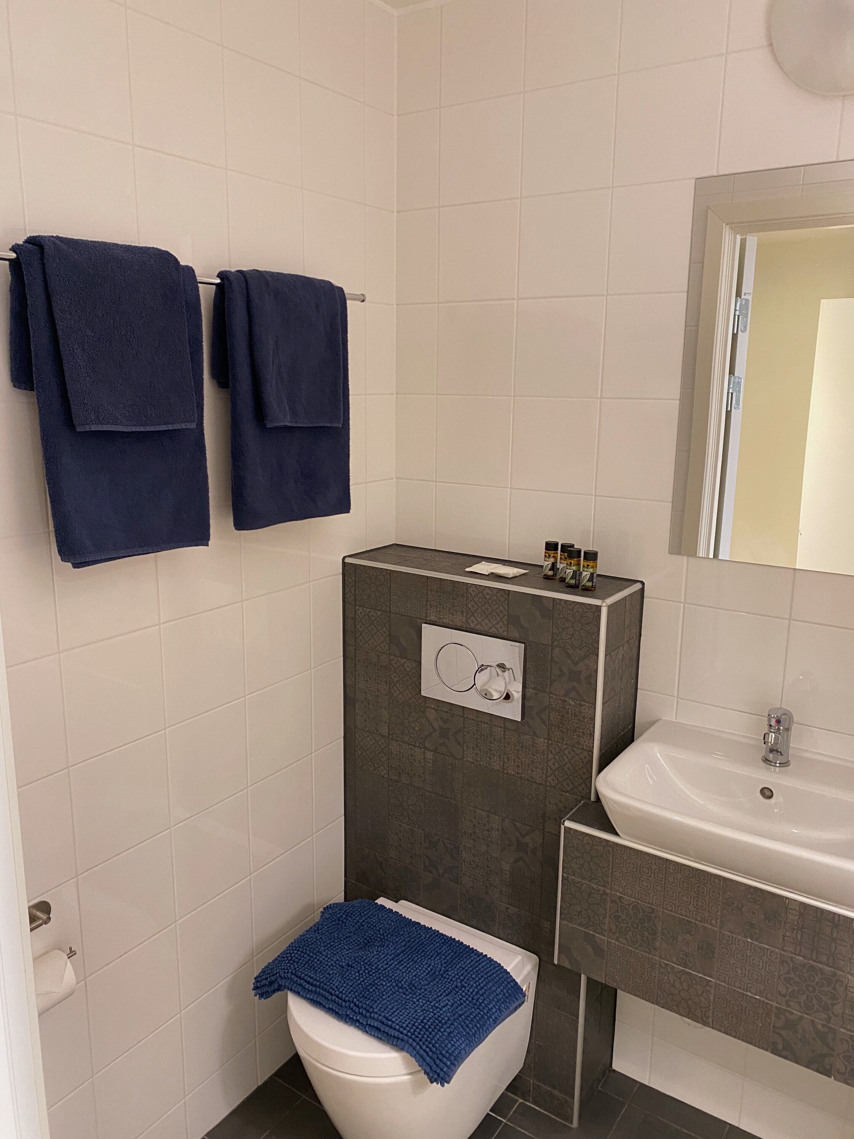 A bathroom with a toilet, sink, and two towels hanging on the wall.