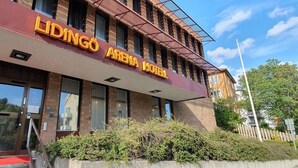 The exterior of the Lidingo Arena Hotel with a red awning, large windows, and a brick facade. -  Lidingö Arena Hotel (Lidingo)